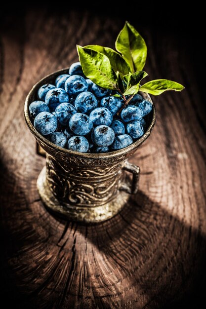 Juicy bilberries in vintage metal bowl on grunge board