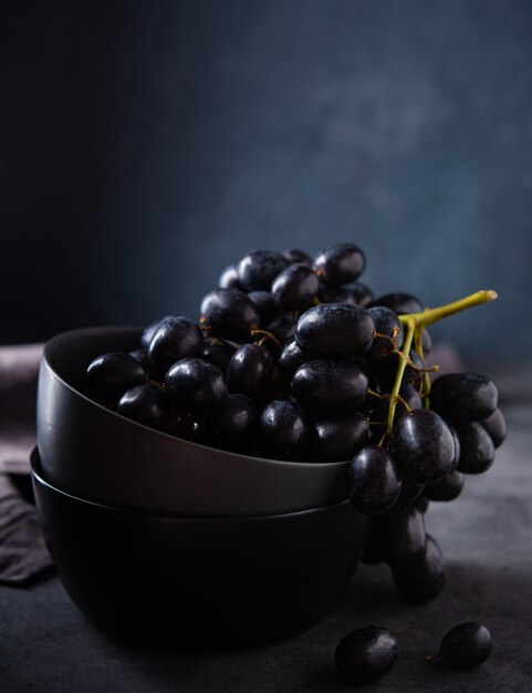 Juicy black grapes in a gray bowl