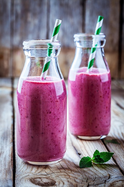 Juicy blackberry smoothies in glass bottles on wooden table