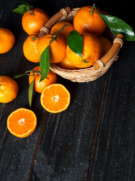 Juicy bright ripe tangerines in wooden basket on dark background