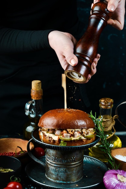 Сочный бургер в руках шеф-повара Бургер с маринованными огурцами и сырным соусом Концепция быстрого питания