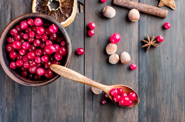 Juicy cranberries in a plate and spice on wood table