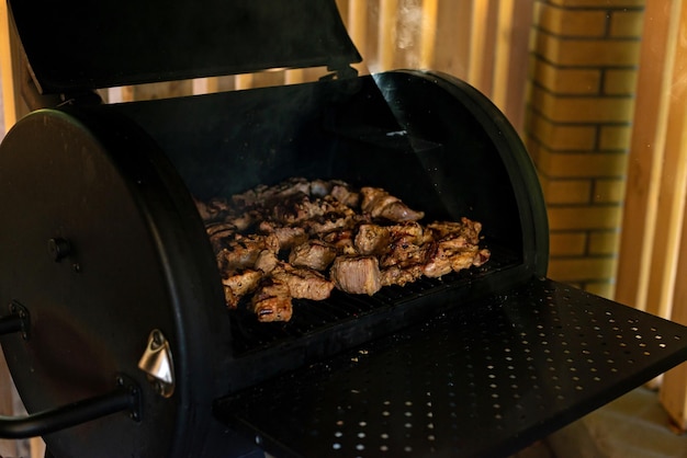 Juicy cuts of beef and pork meat on an open grill. Summer vacation barbecue with friends. Soft selective focus.