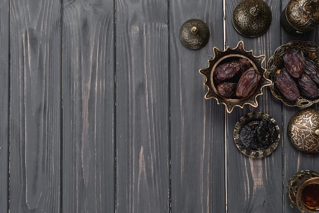 Juicy dates on turkish arabic metallic bowl on wooden plank