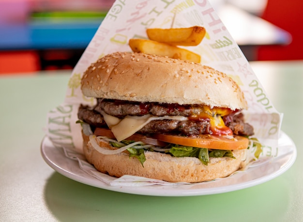 Foto doppio cheeseburger succoso con pancetta, pomodoro, insalata e salse.