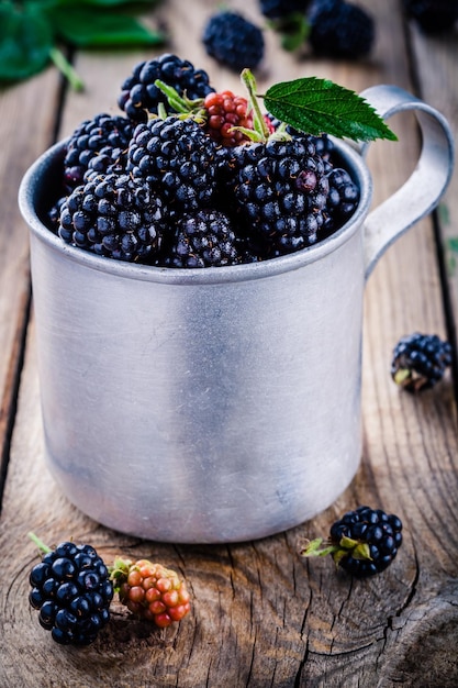 Juicy fresh organic blackberries in old mug on a wooden background