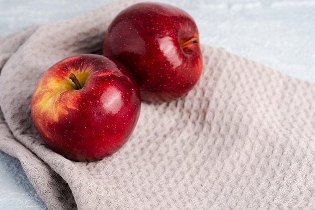 Juicy fresh red apples with water drops on kitchen towel on grey background with copy space