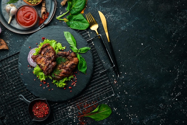 Juicy fried pork steak with spices on a black stone plate Top view Free copy space