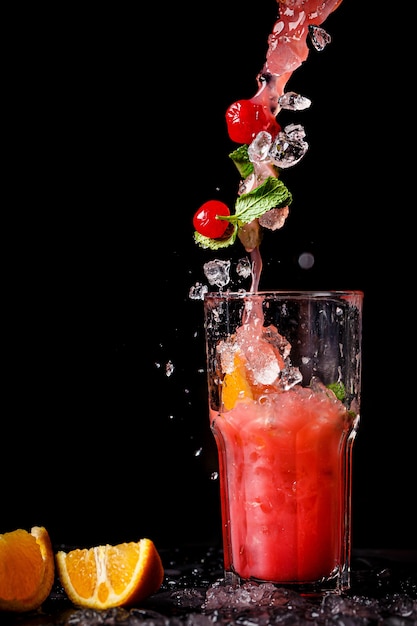 Juicy fruit cocktail is poured into a glass with splashes