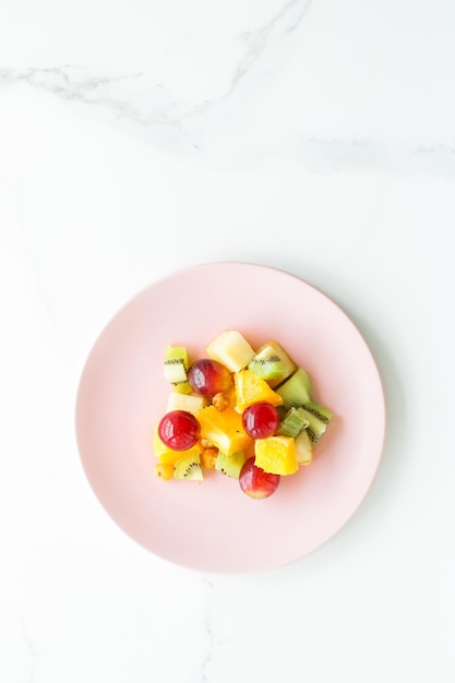 Juicy fruit salad for breakfast on marble flatlay dieting and healthy lifestyle concept