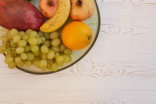 Juicy fruits on a plate on a wooden white table. 