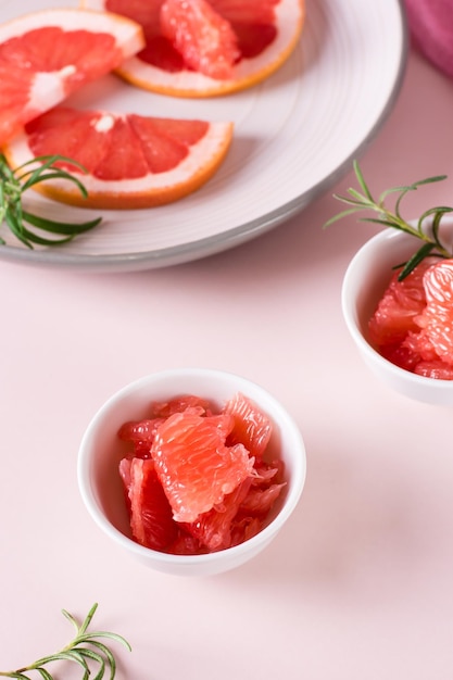 Juicy grapefruit slices and rosemary in a bowl on the table Cocktail ingredients Vertical view