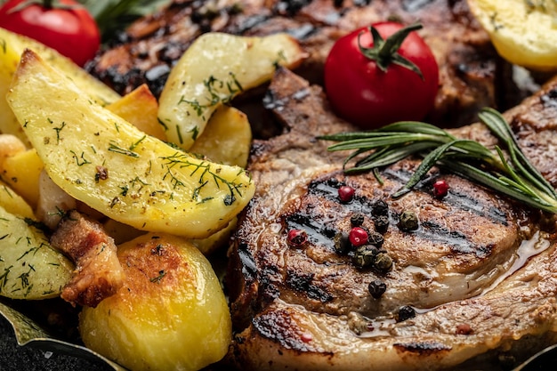 Juicy grilled pork chop with fried potatoes and tomatoes Appetizing pork steak Food recipe background Close up