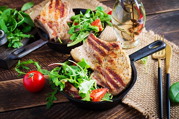 Juicy grilled pork steak with herbs on bone on wooden surface