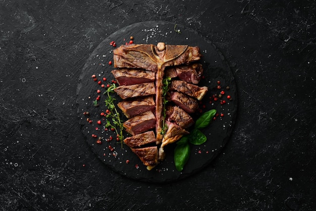 Juicy grilled steak from Angus with spices and herbs on a black background Bull Angus Top view Rustic style