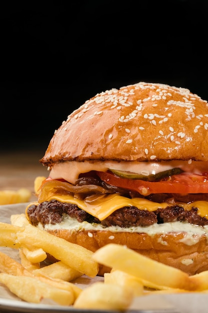 Juicy hamburger with beef patty cheese caramelized onion tomato cucumber tartar sauce and french fries