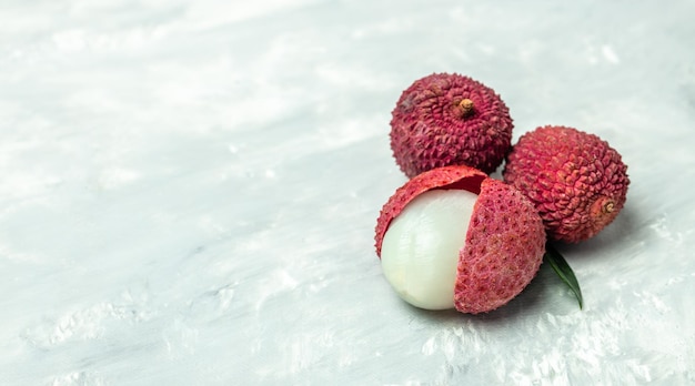 Photo juicy lychee with cut in half and leaves on a light background long banner format top view