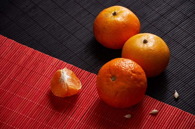 Foto mandarini arancio succosi sul nero con la tavola rossa di stile
