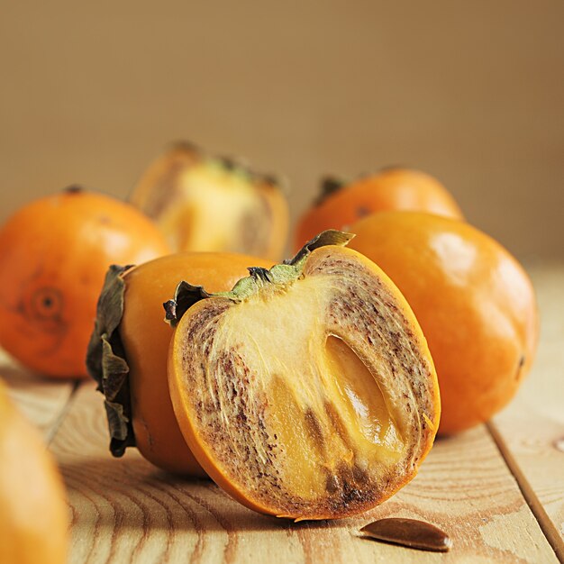 Juicy persimmon half on a wooden table close-up.


