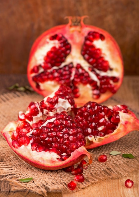 Juicy pomegranate and its half beautiful composition with juicy\
pomegranates on old wooden table