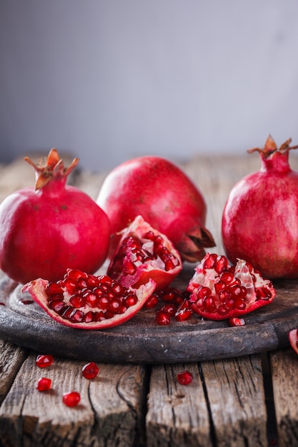 Juicy pomegranates,whole and broken on wooden surface