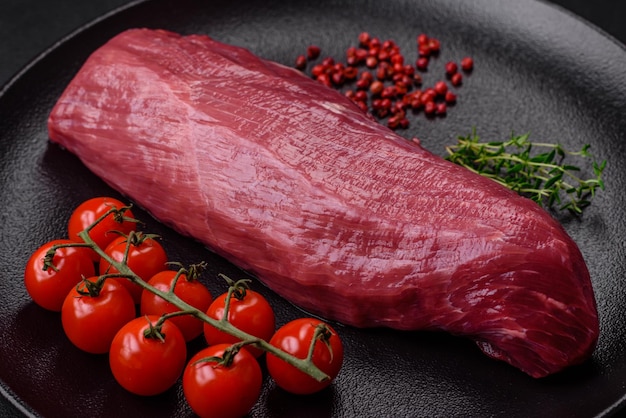 Juicy raw beef with spices salt and herbs on a dark concrete background