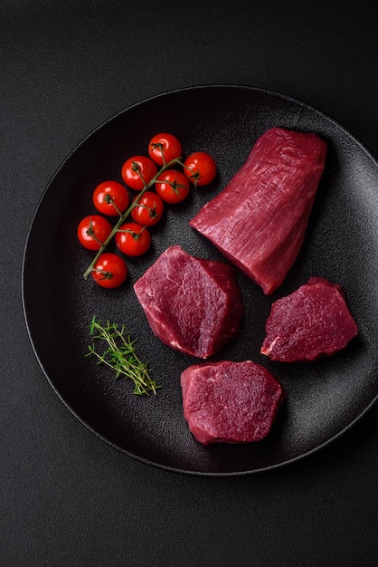 Juicy raw beef with spices salt and herbs on a dark concrete background