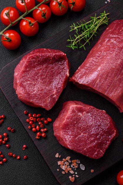 Photo juicy raw beef with spices salt and herbs on a dark concrete background