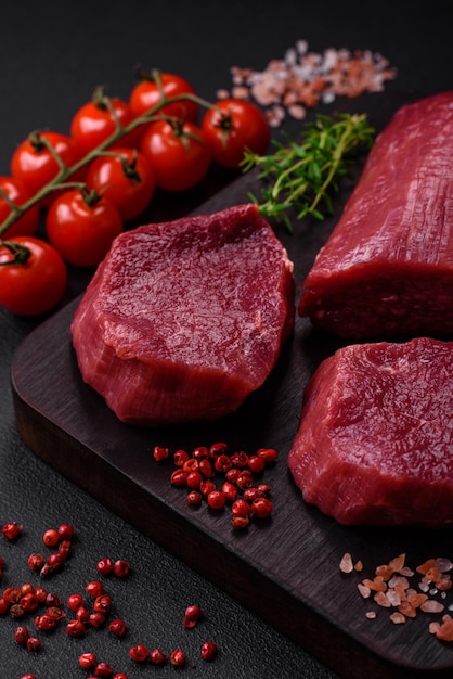 Juicy raw beef with spices salt and herbs on a dark concrete background