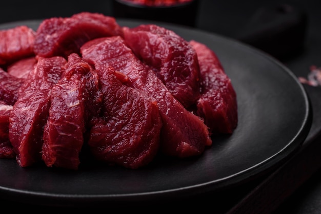 Juicy raw beef with spices salt and herbs on a dark concrete background