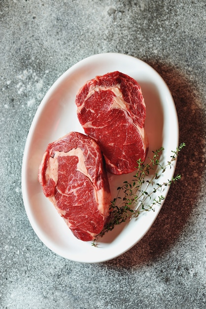 Juicy raw steak with thyme on a plate