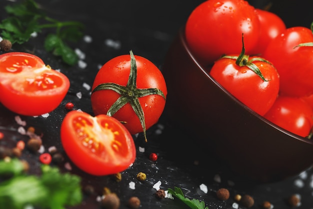 Juicy red cherry tomatoes with spices, coarse salt and greens. Sweet and ripe tomatoes for salads and as ingredients for cooking