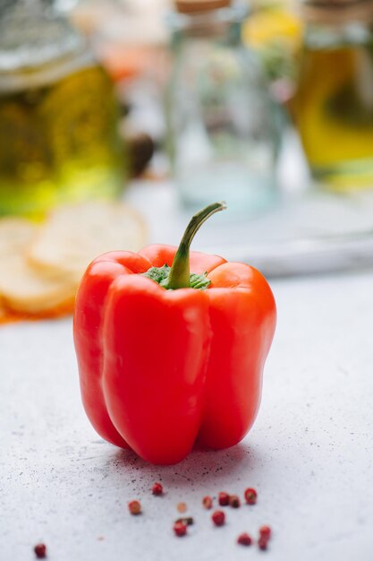 Juicy red paprika pepper in front of oil in bottles blurred in background