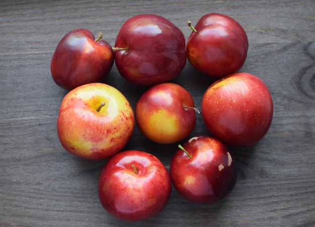 Succose prugne mature rosse su uno sfondo di legno scuro concetto vegano cibo biologico sano