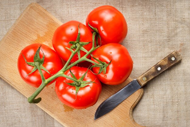 Juicy red tomatoes on a cutting board and a knife