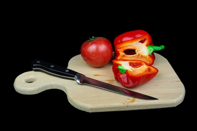 Juicy ripe bell peppers and red tomatoes on a black surface