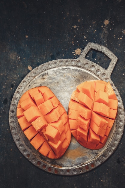 Juicy, ripe mango on a metal plate cut into cubes