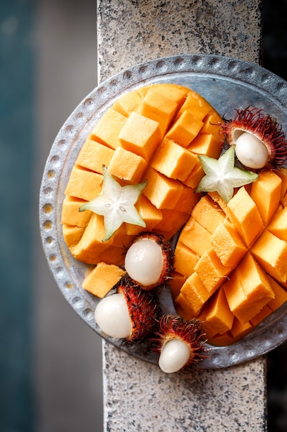 Juicy, ripe mango, rambutan and Cannon on a metal plate