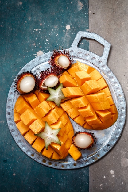 Juicy, ripe mango, rambutan and Cannon on a metal plate