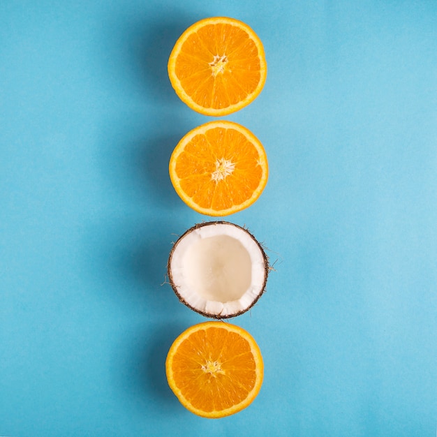 Juicy ripe oranges and open coconut on a bright blue background