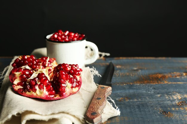 Juicy ripe pomegranate on wooden table on dark background