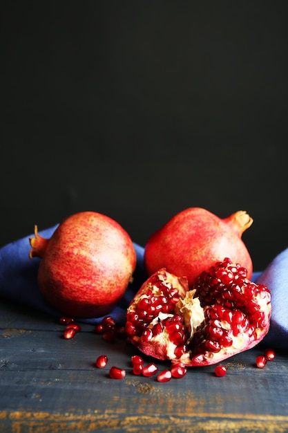 Juicy ripe pomegranates on wooden table on dark background