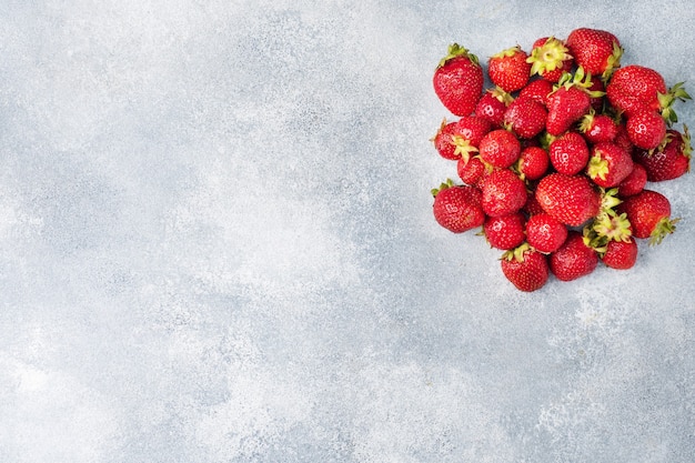 Juicy ripe strawberries on a concrete background. Sweet healthy dessert, vitamin harvest. copy space.