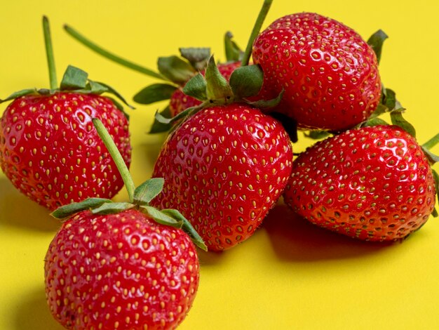 Juicy ripe strawberries lying on a bright yellow background. Healthy and delicious berries, vegetarian food, healthy food