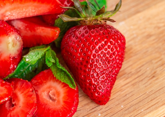 juicy ripe strawberries whole and cut on a wooden board