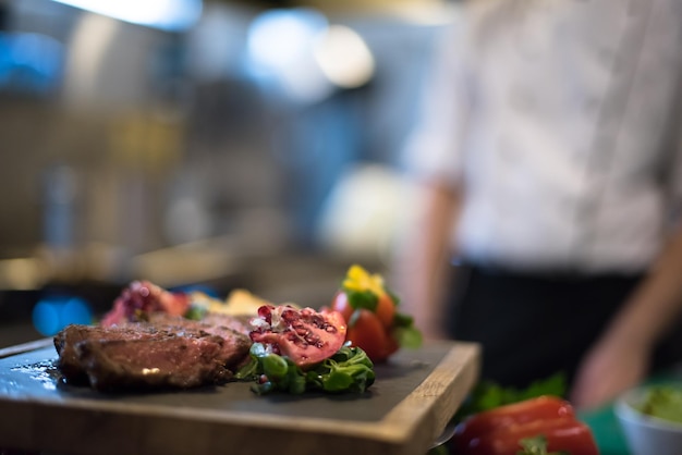 Juicy slices of grilled steak  with vegetables on a wooden board