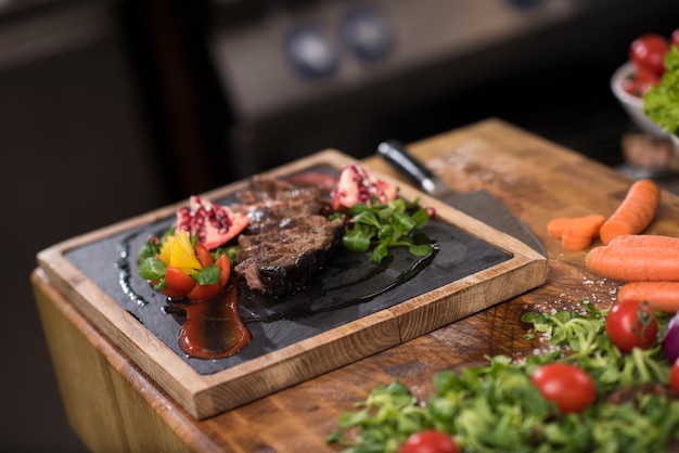 Juicy slices of grilled steak  with vegetables on a wooden board