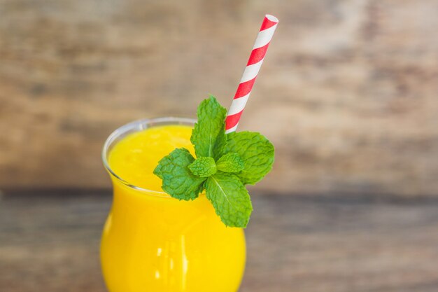 Juicy smoothie from mango in glass with striped straw