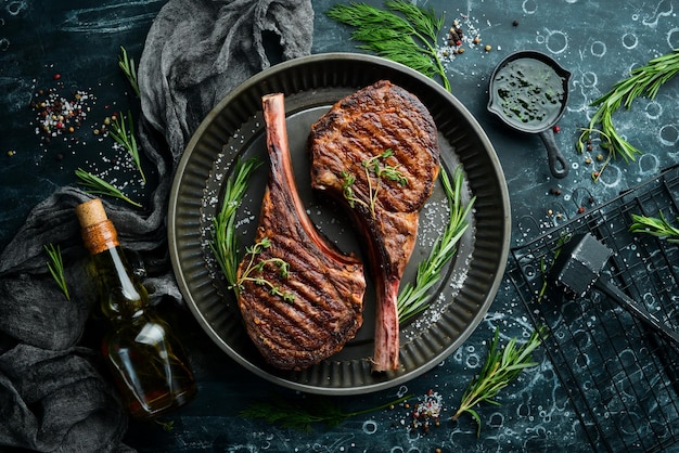 Juicy steak grilled on the bone with spices and herbs On a black stone background Top view Free copy space