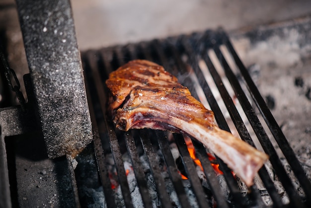 육즙이 풍부한 스테이크는 레스토랑에서 구워집니다. 그릴에 불에 고기를 굽고 있습니다.
